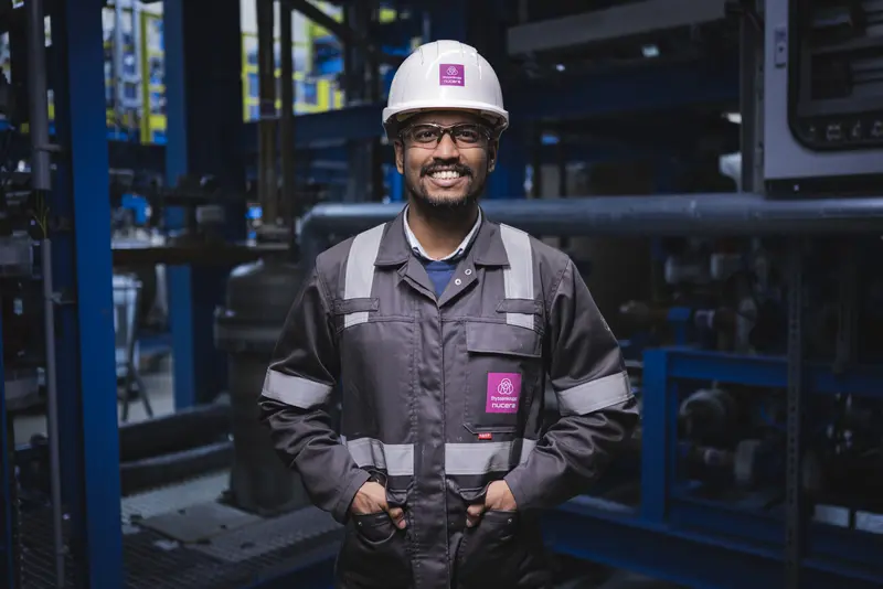 an employee of thyssenkrupp nucera in front of an electrolyzer
